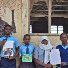 Bakari Ali Mangale (second from left) and his classmates stand alongside his artwork