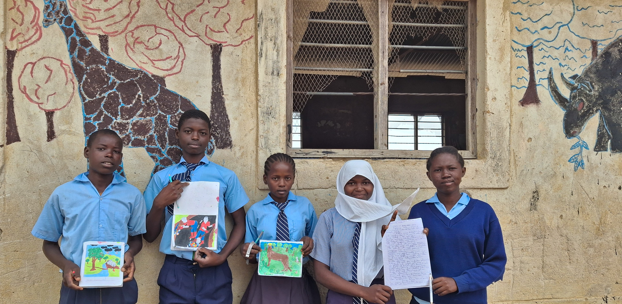 Bakari Ali Mangale (second from left) and his classmates stand alongside his artwork