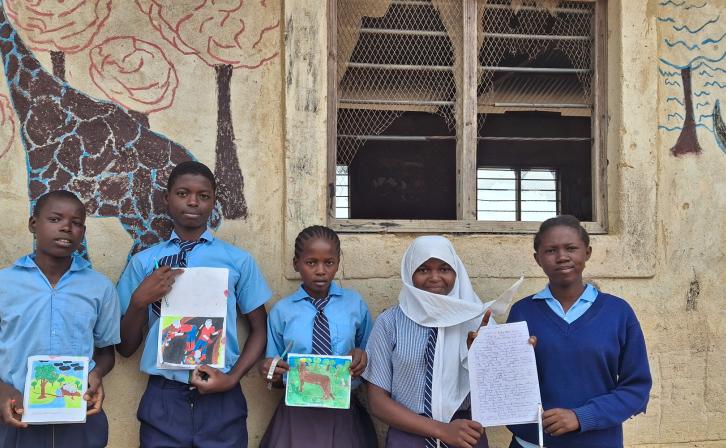Bakari Ali Mangale (second from left) and his classmates stand alongside his artwork