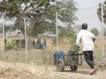 Young boy pushing a barrel of water  from the Rural resource Center in Tchamba